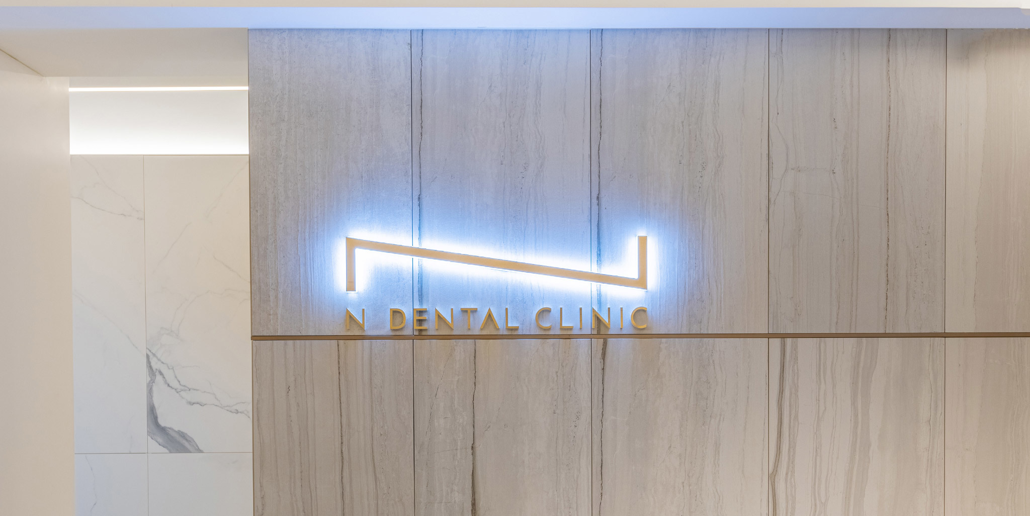 Illuminated sign of NEW N Dental Clinic on a modern stone wall • KOREA NEW N DENTAL CLINIC