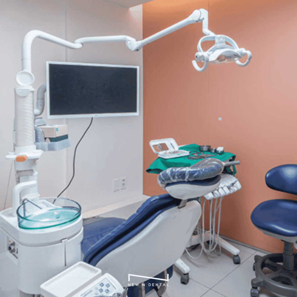 Dentist's office with a dental chair, overhead light, monitor, and various dental instruments on a tray.