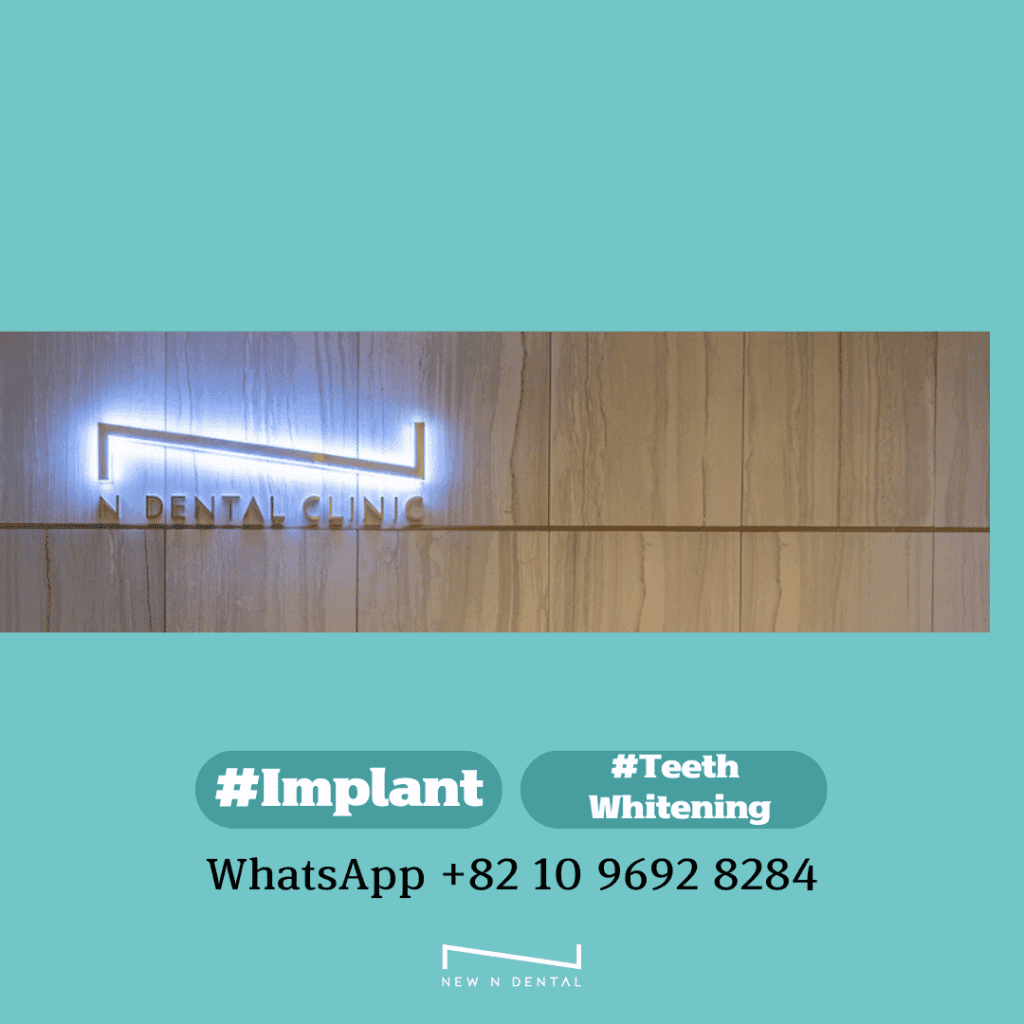 Sign for N Dental Clinic with neon light logo, hashtags #Implant and #TeethWhitening, and WhatsApp contact number +82 10 9692 8284.