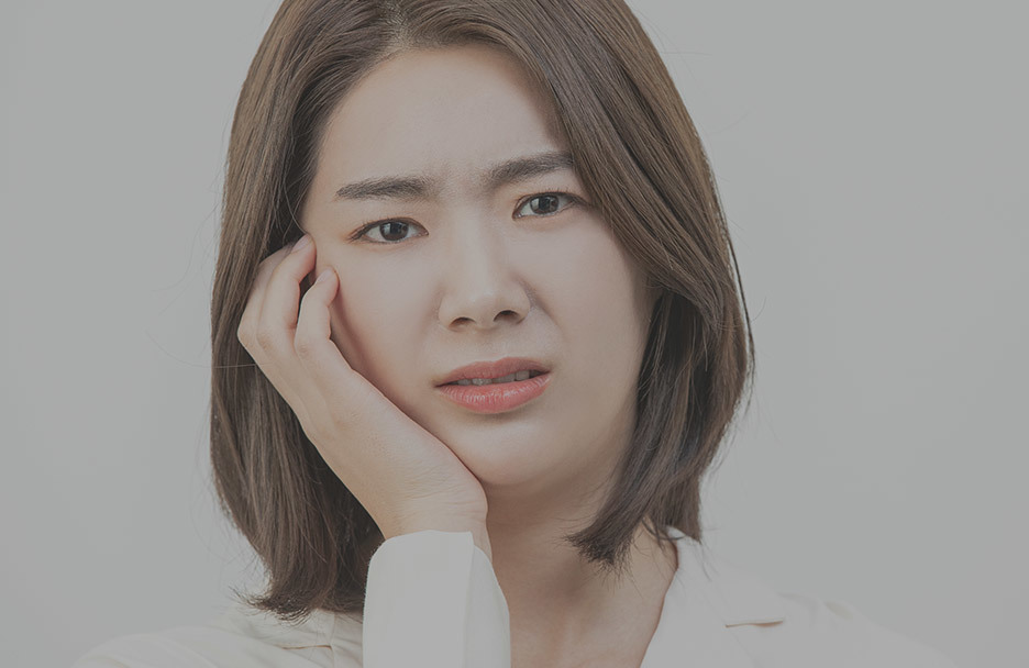 A woman experiencing pain touches her cheek, questioning if wisdom teeth extraction at a university hospital is necessary. Expert insights on wisdom teeth removal. • KOREA NEW N DENTAL CLINIC