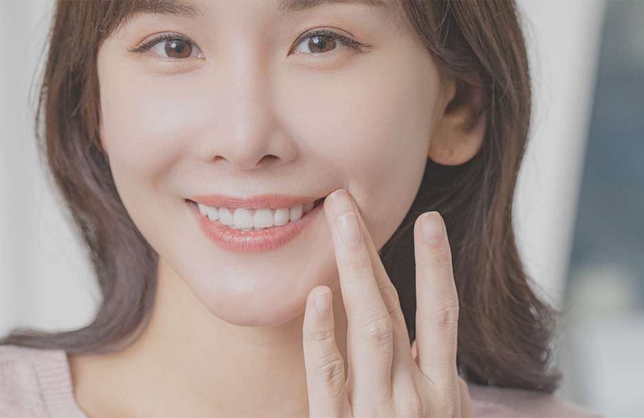 Smiling woman with beautifully white teeth touching her cheek for teeth whitening advertisement • KOREA NEW N DENTAL CLINIC